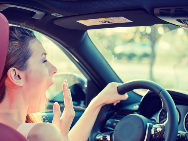 Closeup portrait sleepy, tired, fatigued, exhausted young attractive woman driving her car after long hour trip, isolated street traffic background. Transportation, sleep deprivation, accident concept