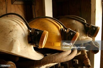 Three mine helmets on a shelf. Main focus on center helmet.