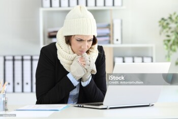 Cold angry executive working at office with a heater failure in winter