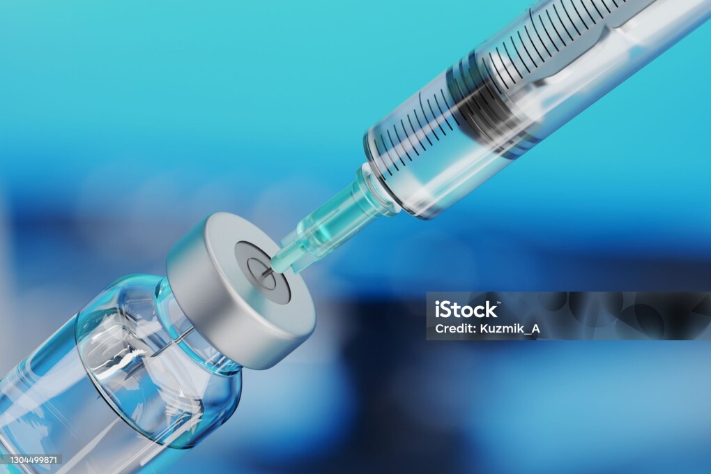 Medical disposable syringe for vaccine injection and glass vial on blue blur background.