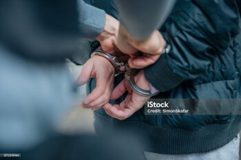 Policeman unlocking a handcuffs on the criminal's back.