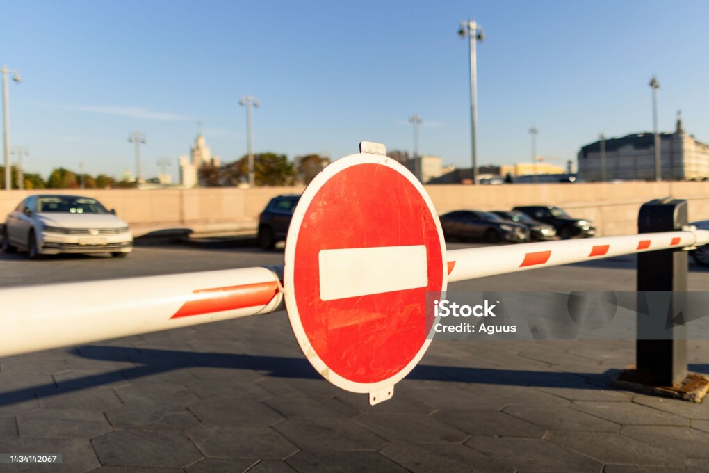 Red round stop sign on an automatic entrance gate on a parking lot