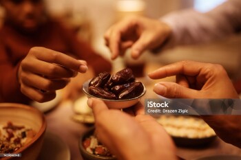 Close up of Muslim family eating dates during Iftar meal at dining table.