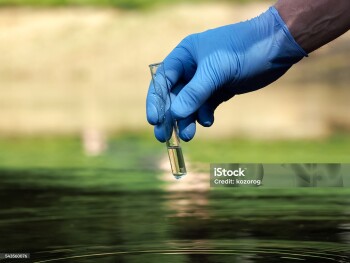 Water sample. Hand in glove holding a test tube of clear water. Concept - water purity analysis, environment, ecology. Water testing for infections, permission to swim