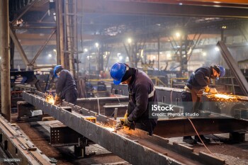 Metal workers using a grinder