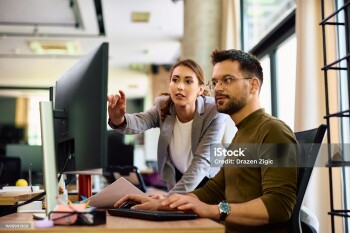 Young entrepreneur and his female coworker using desktop PC while working in the office.