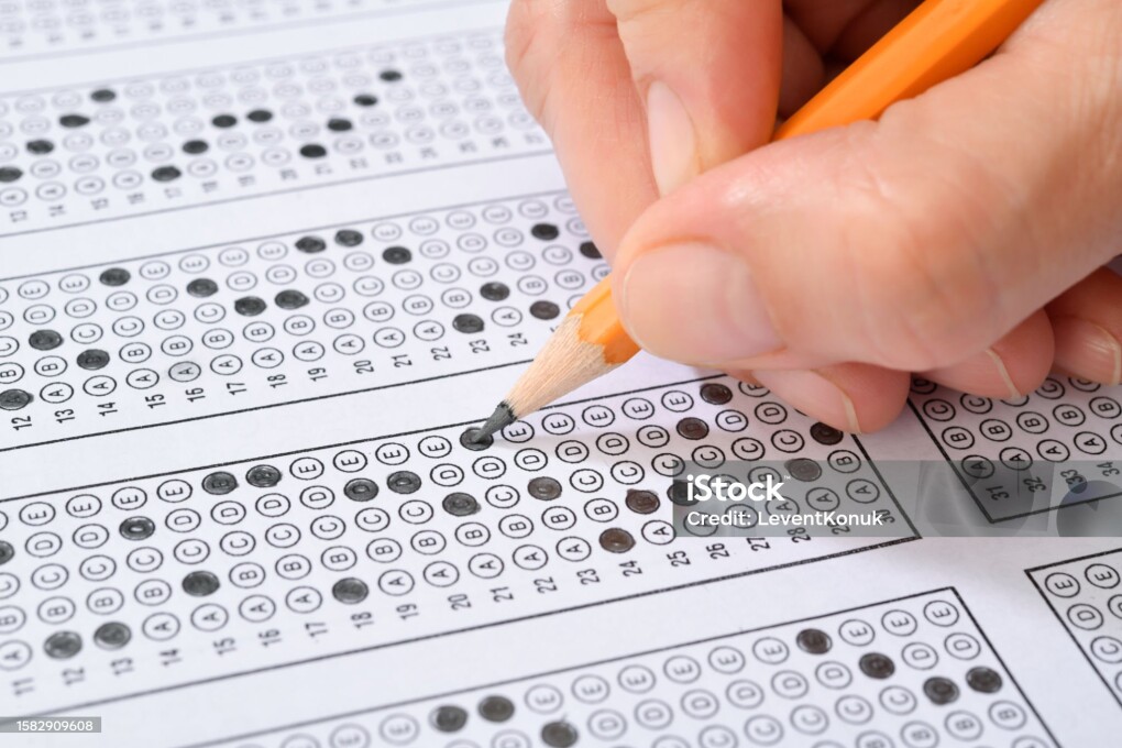 Student filling out answers to a test with orange pencil close-up