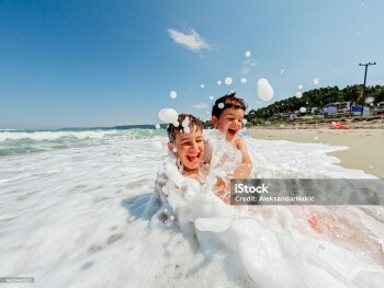 Photo of two young boys rushing into the sea water and having fun with waves