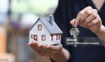 Real estate agent or financial advisor holding small house model and keys. Real estate investors, purchase and mortgage concept.