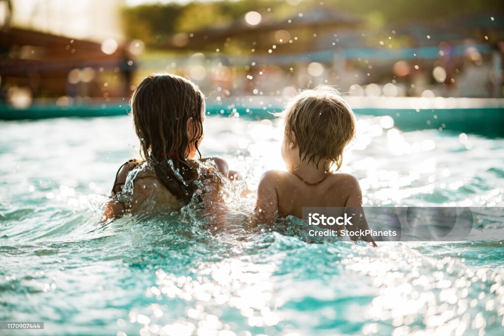 Rear view kids enjoying splashing in the pool