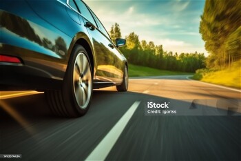 Low angle side view of car rushes along the highway at sunset