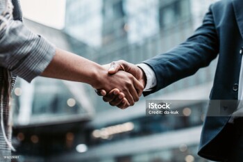 Meeting success. Two business persons shaking hands standing outside