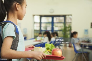 School girl holding food tray in school cafeteria