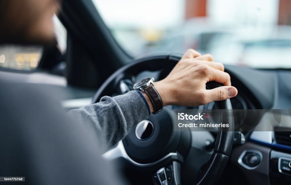 A close up view of an unrecognizable Caucasian male working as a taxi driver.