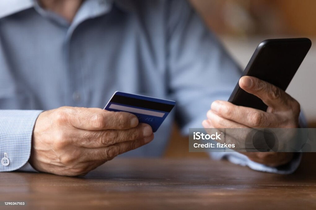 Close up senior man holding smartphone and plastic credit or debit card, mature customer paying online in store, entering information, browsing banking service, making secure internet payment