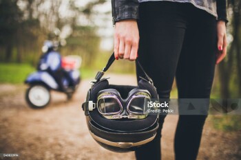 Young attractive girl holding retro helmet, retro scooter from 1984 year in background