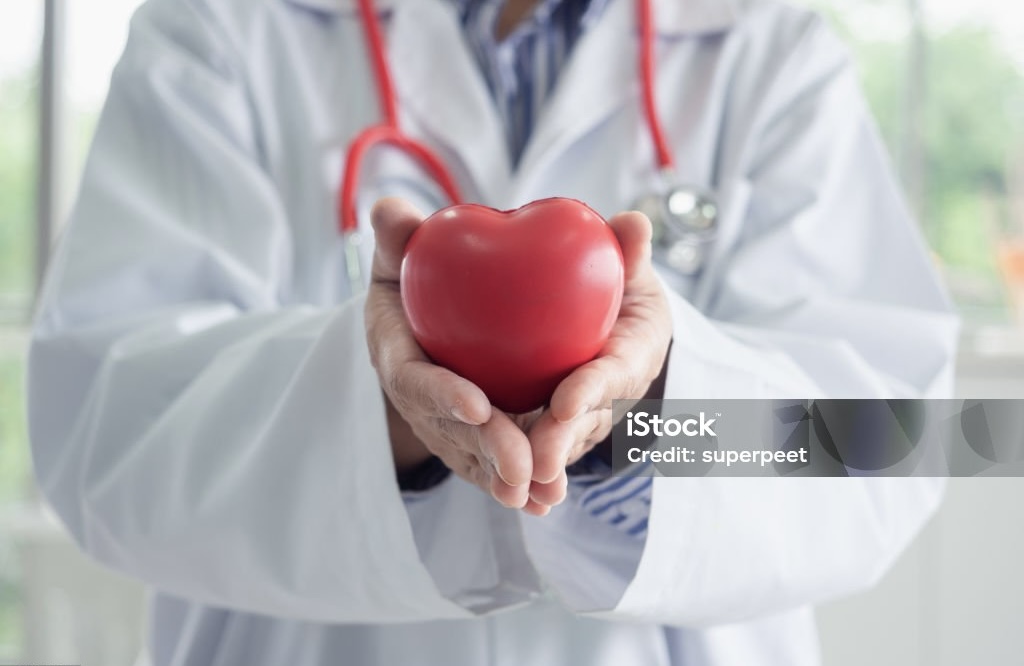 Young woman doctor holding a red heart in lab