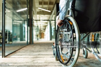 Paralyzed man in a wheelchair on the move in the disabled office building.