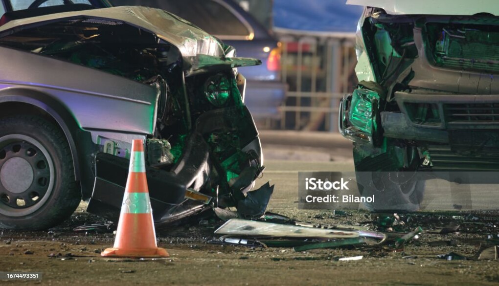 Damaged in heavy car accident vehicles after collision on city street crash site at night. Road safety and insurance concept.