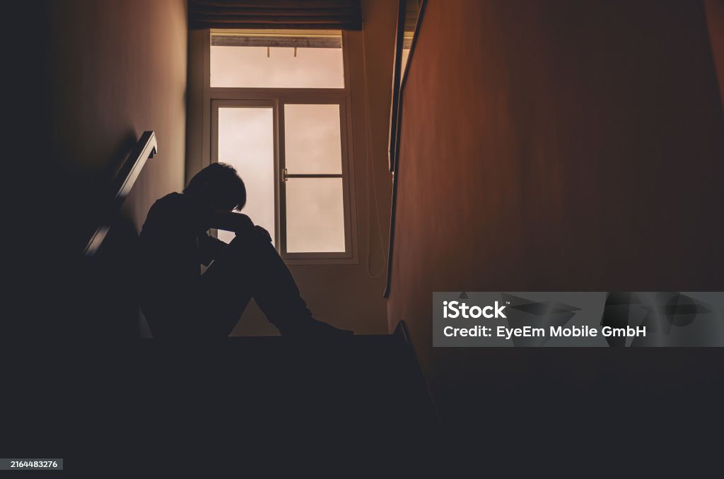 Silhouette Man Sitting By Window On Steps At Home