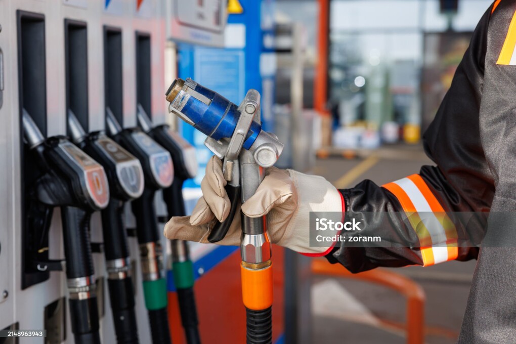 Hand in protective glove holding the nozzle at fuel pump, refueling LPG (liquefied petroleum gas) at a gas station