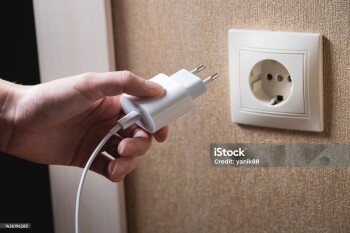 A young woman inserts a plug into a socket. A young woman plugs a charger or electrical appliance power cord into a socket. High quality photo.