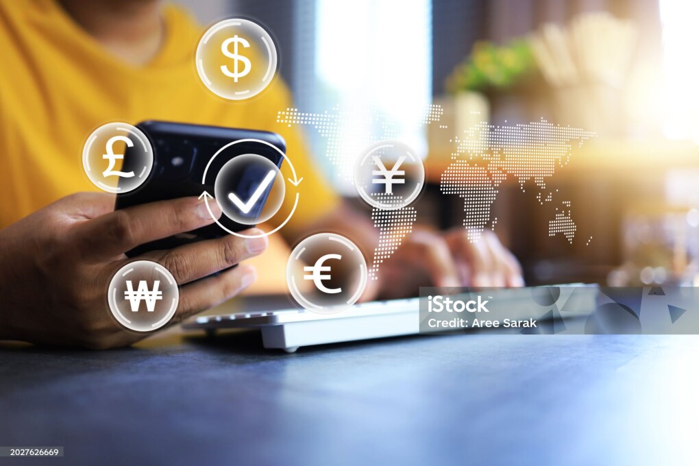 Currency exchange and mobile banking transaction concept with man in yellow t shirt using smart phone to transfer money by application for international transaction