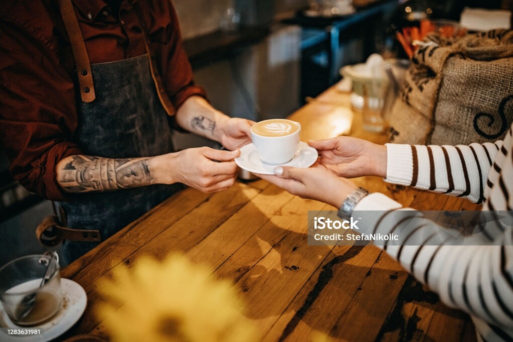 Barista giving coffee cup to client