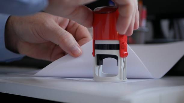 Businessman Hand Stamping Papers and Documents Using a Rubber Stamp, Office Job with Files and Contracts.