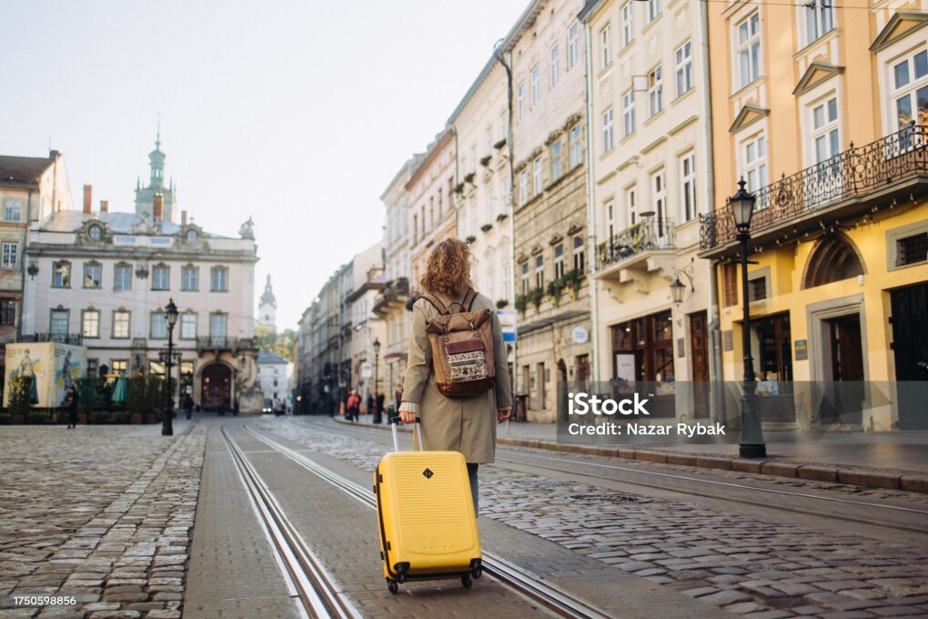 A beautiful and cheerful woman is captured as she walks along a charming, ancient European street during the autumn season