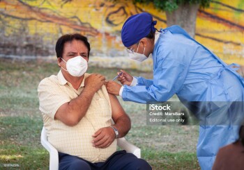 Tepoztlán, Morelos, Mexico - April 21, 2021: Covid-19 vaccination campaign in Mexico. Public health personnel vaccinating senior people against COVID-19 with the Pfizer vaccine, at a pop-up vaccination center on a soccer field, to prevent the spread of the virus among the mexican population.
