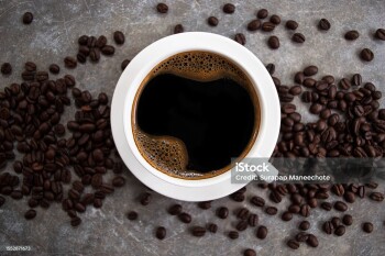 Top view black coffee in a white glass placed on an old cement table with coffee beans.