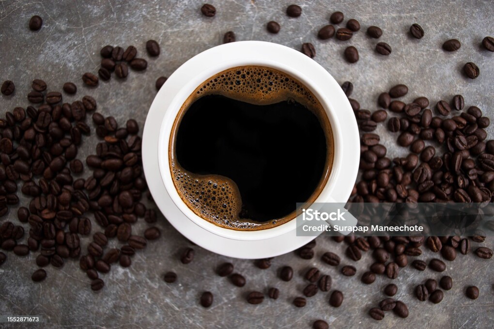 Top view black coffee in a white glass placed on an old cement table with coffee beans.