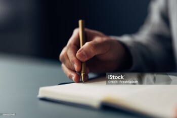 An individual meticulously jotting down notes in a notebook using an elegant pen, with a close-up on the writing hand.