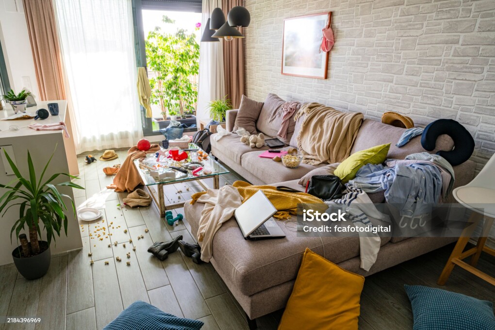 Upset woman head in hands contempling her messy and dirty living room