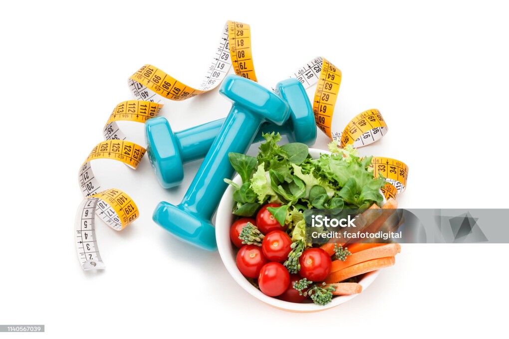 Healthy food and fitness concept: Top view of a bowl filled with fresh organic vegetables salad shot on white background. Dumbbell weights and a tape measure are around the salad bowl. High key DSRL studio photo taken with Canon EOS 5D Mk II and Canon EF 100mm f/2.8L Macro IS USM.
