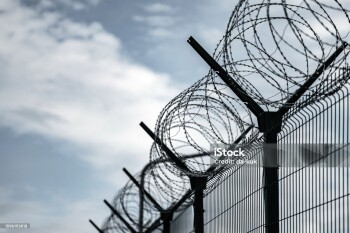 Barbed Wire Fence. Prison or border fence with razor wire against dark sky. Security concept