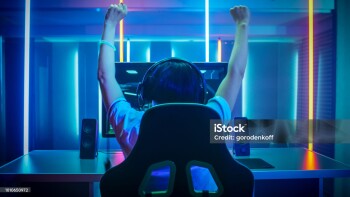 Professional Gamer Playing and Winning in First-Person Shooter Online Video Game on His Personal Computer. Footage Fade out into Bokeh. Room Lit by Neon Lights in Retro Arcade Style. Cyber Sport Championship.