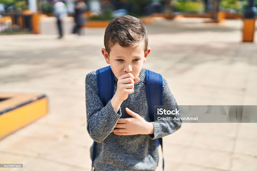 Blond child student coughing at park