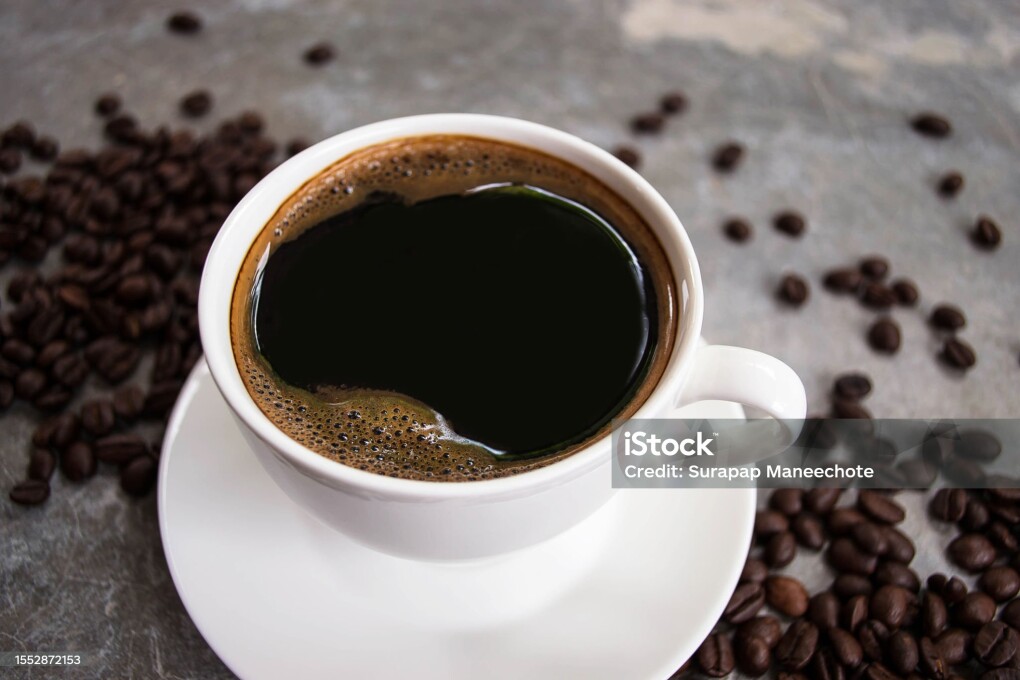 Side view black coffee in a white glass placed on an old cement table with coffee beans.