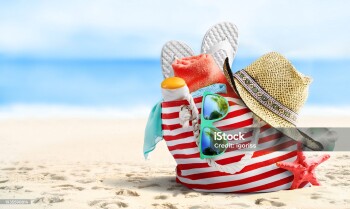 Summer vacations concept background. Beach bag, straw hat, flip flops, sunglasses and starfish on sandy beach and azure sea on background.