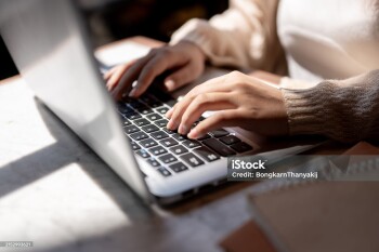 Close-up image of a woman typing on laptop keyboard, working on her laptop computer at a table indoors on a sunny day. businesswoman, student, digital nomad, working remotely