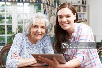 Teenage Granddaughter Showing Grandmother How To Use Digital Tablet