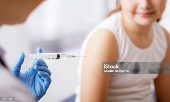Doctor giving an injection to a young patient, the girl is smiling and relaxed