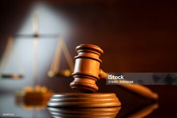 Judge’s gavel and scale on the shining wooden brown table and the brown background.
