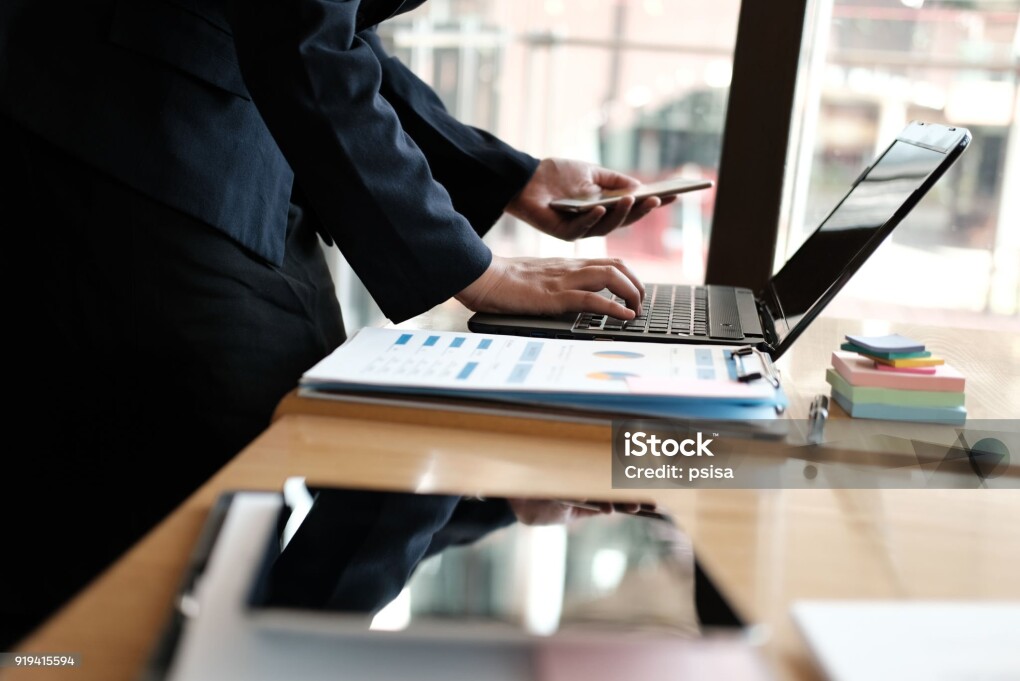 businesswoman holding mobile phone at office. young female entrepreneur using smartphone at cafe. freelance woman working with computer at coffee shop. business concept