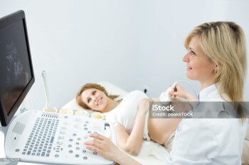 Happy woman looking at ultrasound results with her doctor in examination room