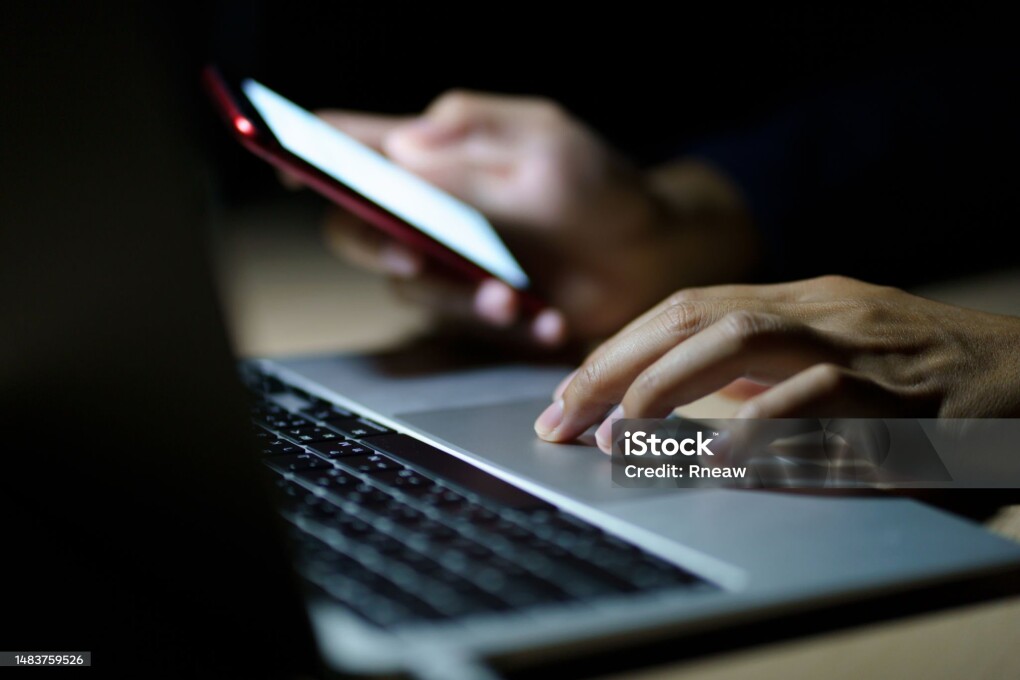Business man using smart phone, tablet in Dark room. hand holding smart phone , tablet. lap top in front of him.