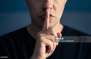 Secret and silence. Quiet silent shh gesture with finger on lips. Man doing expression with hand on mouth. Taboo topic, censorship or freedom or speech. Conspiracy theory. Confidential talk.