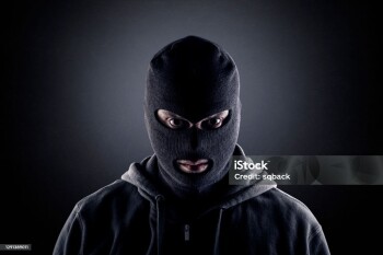 Criminal wearing black balaclava and hoodie in the dark